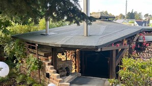 Eine kleine, rustikale Außenstruktur mit Backsteinmauer, Holztür und Metalldach.