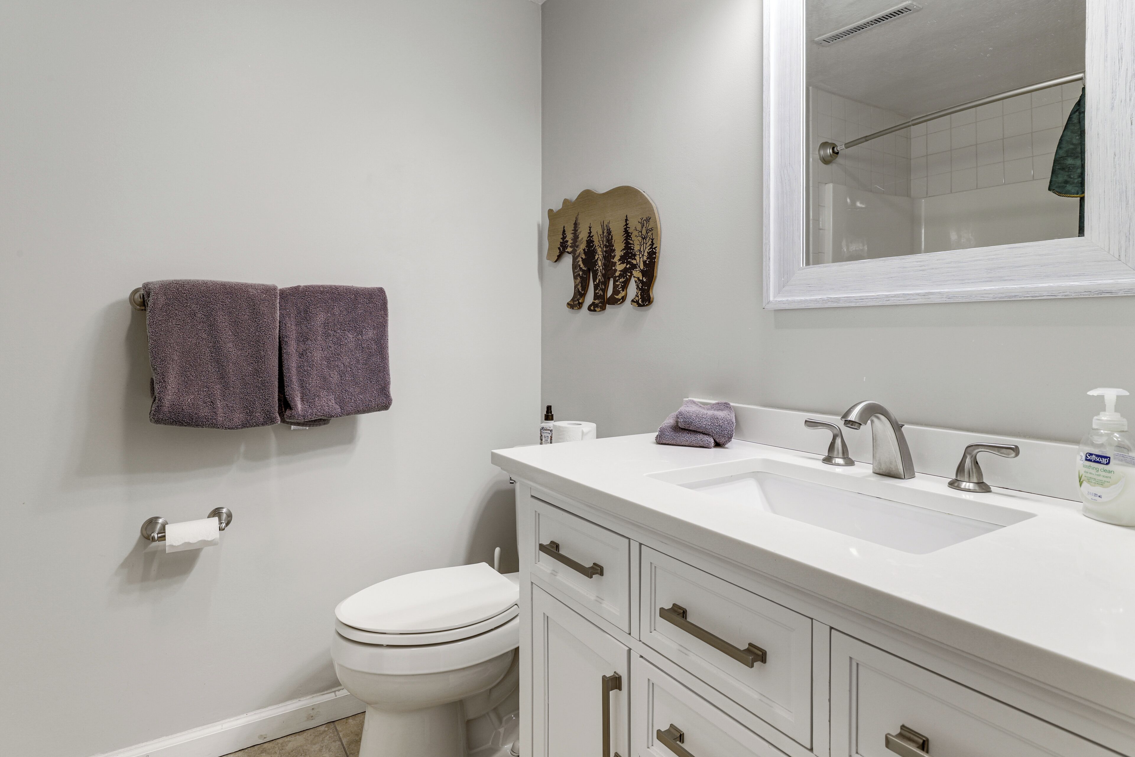 A bathroom with a white sink, a mirror, a toilet, and two towels hanging on the wall.