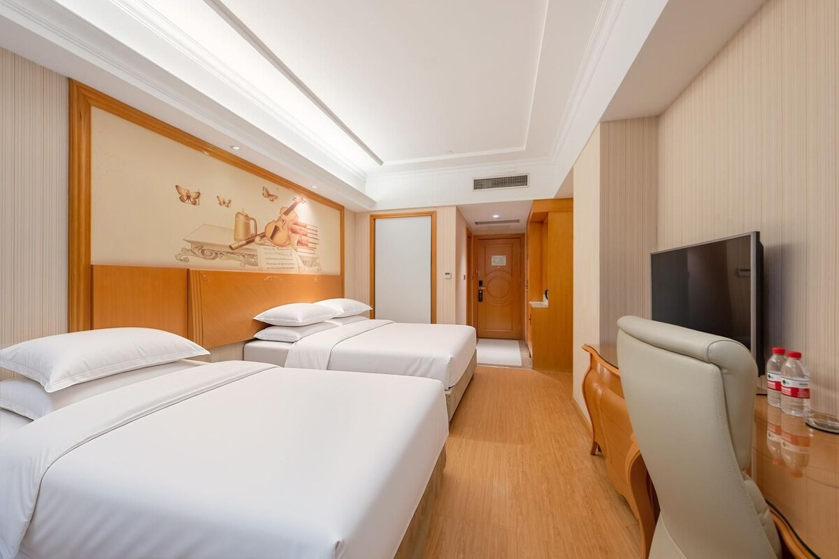 Ein Hotelzimmer mit zwei Betten, einem Fernseher und einem hölzernen Kopfteil.