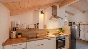 Una cucina con travi in legno, un frigorifero in acciaio inox, un forno a microonde, un fornello e un lavello.