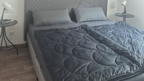 A neatly made bed with a quilted cover, a bedside lamp, and a small table with a lamp.