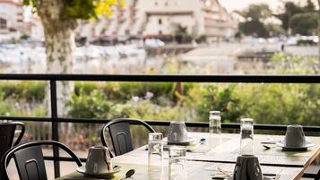 A table set for dining with chairs, a view of a marina with boats, and a building in the background.