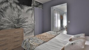 A bedroom with a bed, a dresser, a mirror, and a door leading to another room.