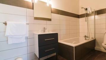 Une salle de bain moderne avec un lavabo blanc, un meuble-lavabo aux tons foncés, une baignoire et des toilettes.