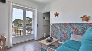 A room with a balcony, a sofa, a small table, and a wall with two turtle decorations.