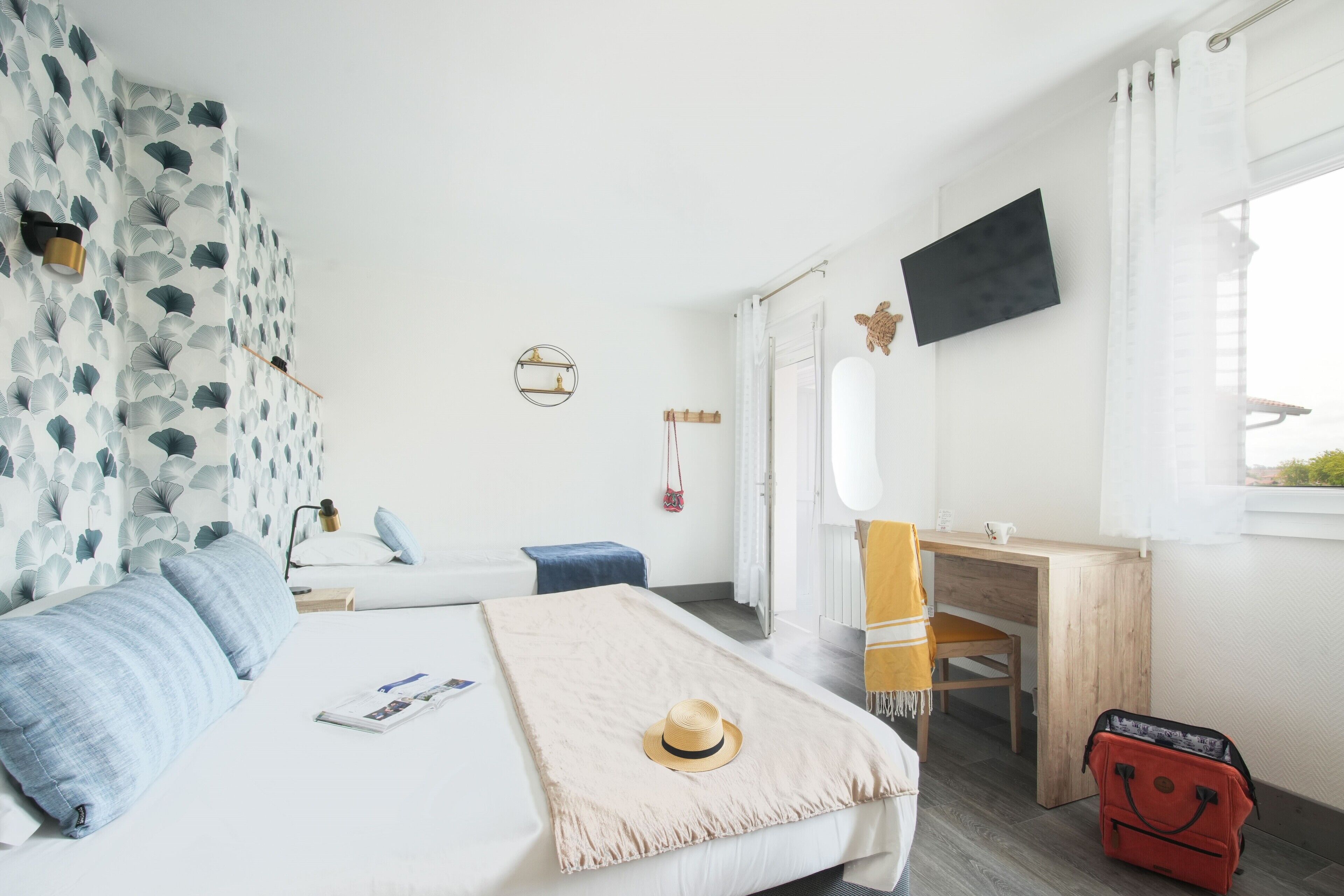 Een slaapkamer met een bed, een bureau, een stoel, een televisietoestel en een koffer.