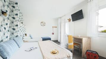 Een slaapkamer met een bed, een bureau, een stoel, een televisietoestel en een koffer.