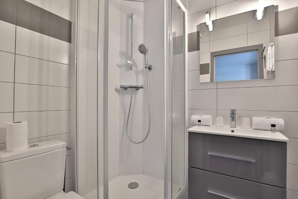A modern bathroom with a glass-enclosed shower, a toilet, and a vanity with a mirror.