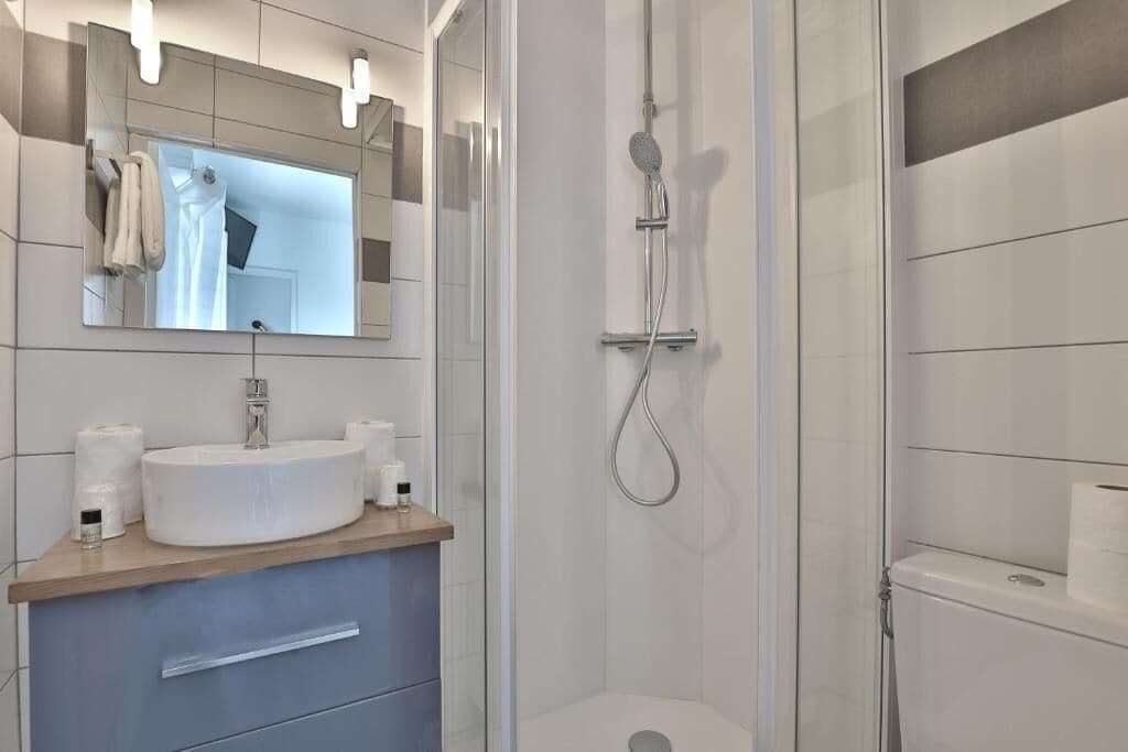 Un baño moderno con lavamanos, espejo y ducha.