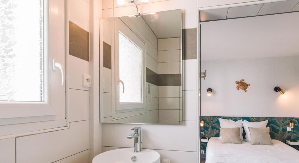 Un baño moderno con un espejo grande, un lavamanos y una zona de ducha.
