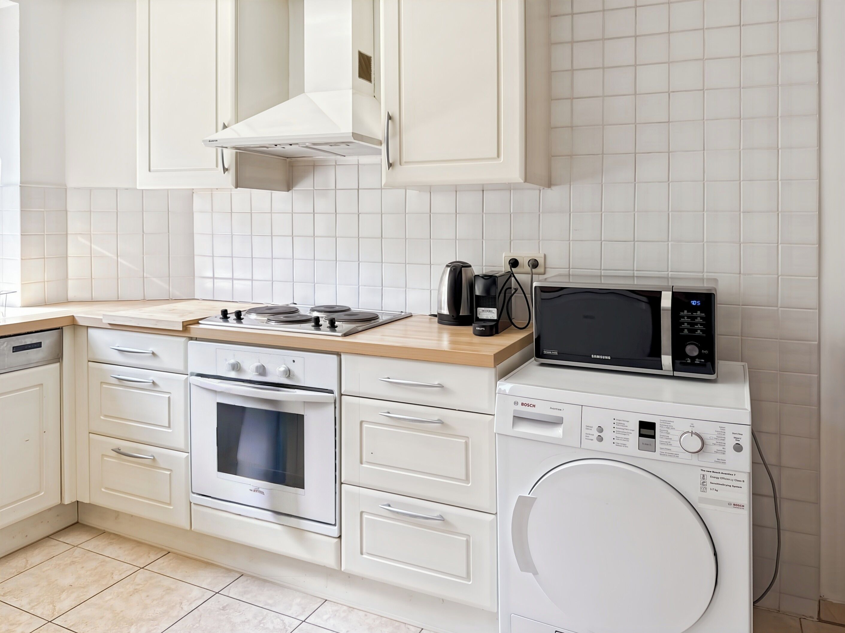 Une cuisine moderne équipée d’une cuisinière, d’un four, d’un four à micro-ondes et d’un lave-linge.