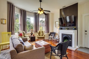 A living room with a sofa, chairs, a fireplace, a TV, and a ceiling fan. - 1 Mi to SCAD! Historic Savannah Haven w/ Patio (Savannah)