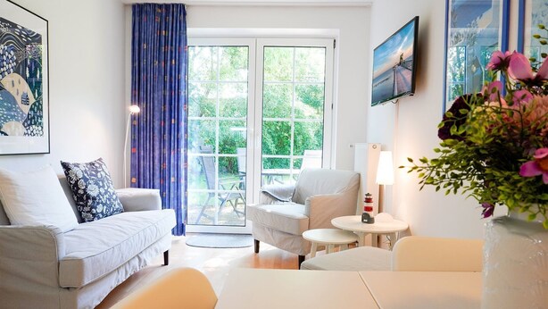 A modern living room with a sofa, armchair, and a small table with a lamp. - Lotte Vacation Rental - Lotte Vacation Rental for up to 4 people (non-smoking) (Timmendorfer Strand)
