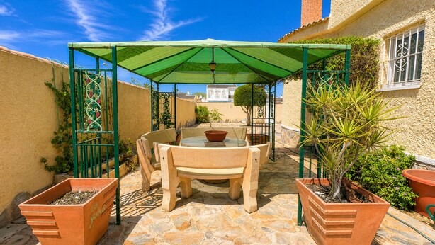 A patio with a table and chairs, a green canopy, potted plants, and a stone floor. - Private Pool Villa in El Chaparral (El Chaparral)
