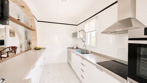A modern kitchen with white cabinetry, a black stove, and a built-in oven. - Private Pool Villa in El Chaparral (El Chaparral)