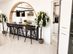 Une cuisine moderne dotée d’un îlot central, de tabourets de bar, de plantes en pot et d’un grand élément décoratif en briques en forme d’arc.