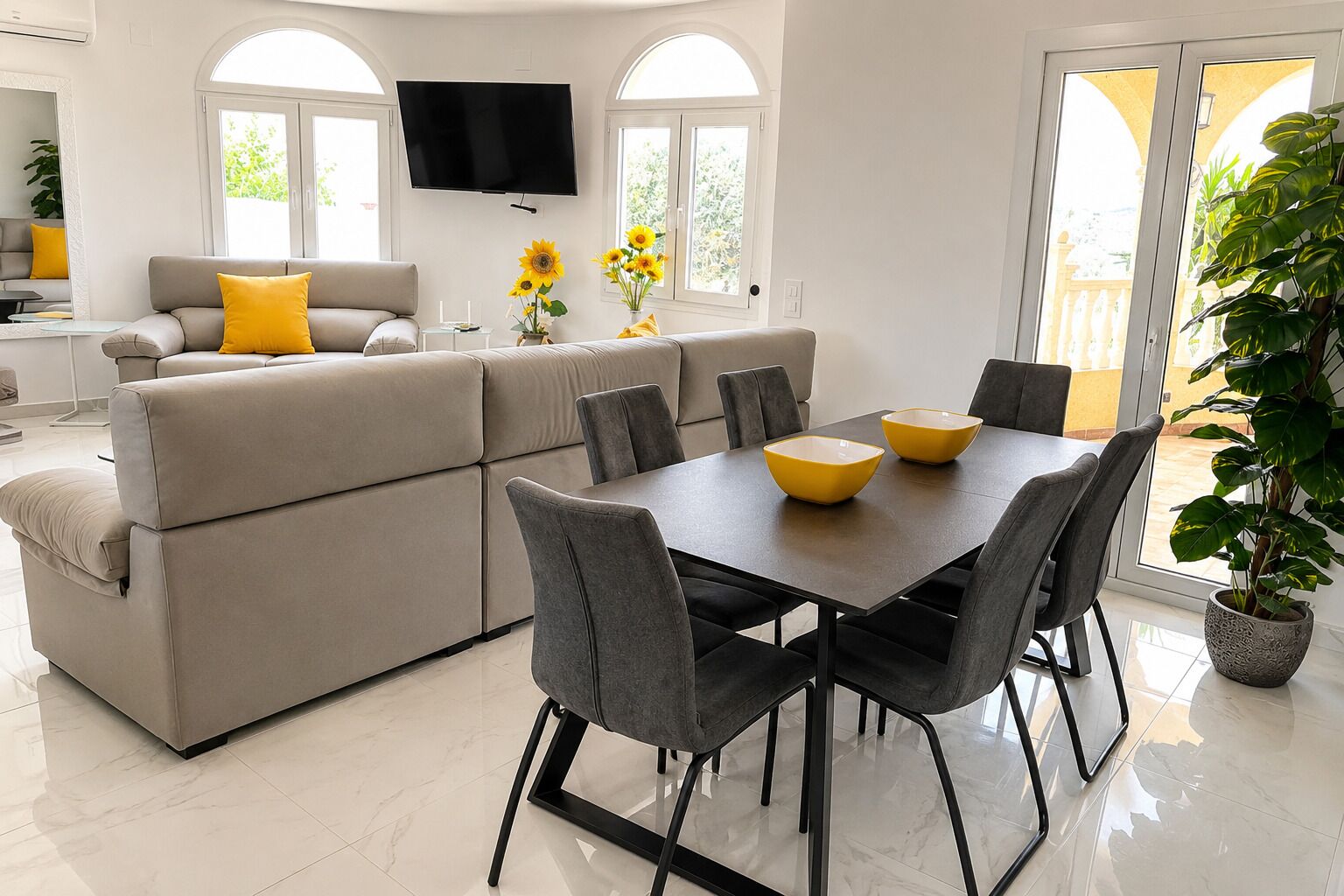 A modern living room with a sofa, dining table, chairs, a TV, and a large window.