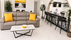 A modern living room with a sofa, coffee table, and dining area with bar stools. - Private Pool Villa in El Chaparral (El Chaparral)