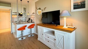 Eine moderne Küche mit einer zentralen Kochinsel, Barhocker, einem Flachbildfernseher und einer Lampe.