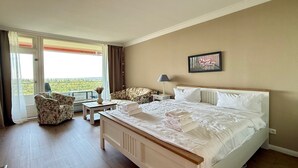 Ein Hotelzimmer mit einem Bett, einem Sessel, einem Tisch, einer Lampe und einem Gemälde.