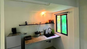 A compact kitchen with a countertop, a sink, a small refrigerator, and a window with a view. - A peaceful cozy home, will truly refresh your soul (Maret)