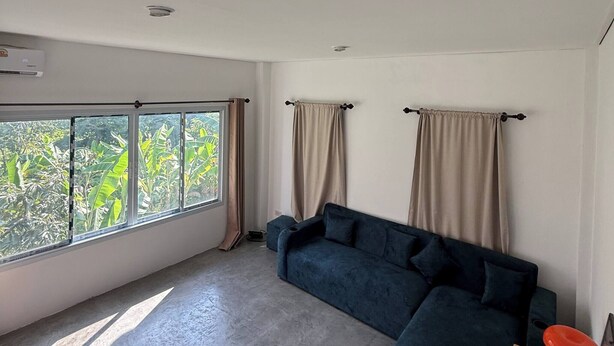 Ein Wohnzimmer mit großem Fenster, einer Couch und einem Holztisch.