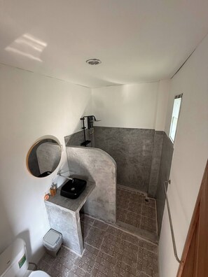 Une salle de bain équipée d’une douche, d’un lavabo, de toilettes et d’un miroir.