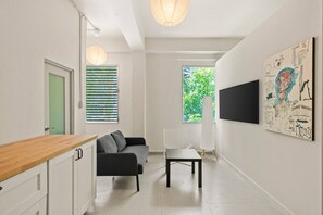 Une pièce moderne comprenant un canapé, une table, un téléviseur et des œuvres d’art accrochées au mur.