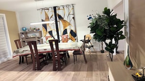 A dining area with a wooden table and chairs, a decorative wall, and a potted plant. - Chris          Manor (Saint-Augustin-de-Desmaures)