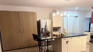 A modern kitchen with a central island, bar stools, a microwave, and a refrigerator. - Chris          Manor (Saint-Augustin-de-Desmaures)