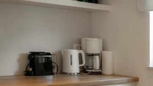 En köksbänk med en kaffebryggare, en vattenkokare och en rulle hushållspapper.