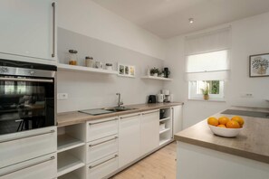 Cuina moderna amb armaris blancs, forn integrat i finestra amb vistes.