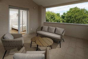 A balcony with a sofa, two chairs, a small table, and a sliding glass door leading to a bedroom. - Villa Lykka (100631-K1) - Kastelir (Kastelir)