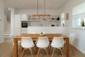 Una cucina moderna con mobili bianchi, un tavolo da pranzo in legno e quattro sedie bianche.