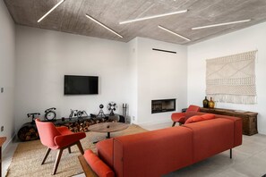 Ein modernes Wohnzimmer mit einer Couch, Sesseln, einem Kamin, einem Fernseher und einer Wanddekoration aus Makramee.