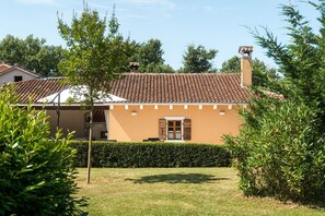 Ein Haus mit Ziegeldach, einer kleinen Veranda und einem gepflegten Rasen.