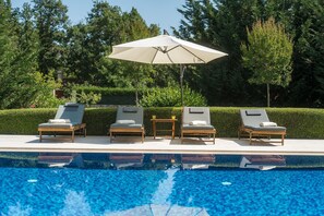 Ein Poolbereich mit Liegestühlen, einem Tisch und einem Sonnenschirm.
