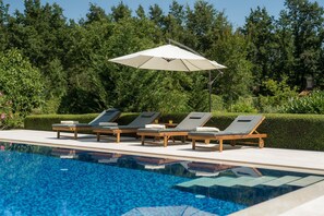 Ein Schwimmbad mit Liegestühlen und Sonnenschirm.