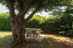 Ein Picknicktisch unter einem großen Baum in einem Garten.
