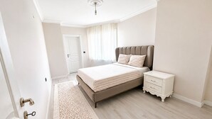 A bedroom with a bed, nightstand, and a door. - Luxury 2+1 Apartment, 1st Floor – 15 Minutes to the Airport (Arnavutköy)