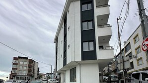 A multi-story building with a flat facade, balconies, and a ground-level entrance. - Luxury 2+1 Apartment, 1st Floor – 15 Minutes to the Airport (Arnavutköy)
