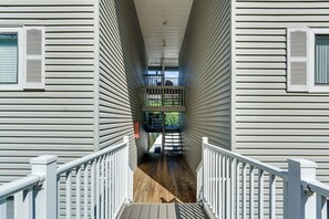 Ein Korridor mit Holzboden und weißen Geländern, der zu einem Balkon mit Blick auf Grünflächen führt.
