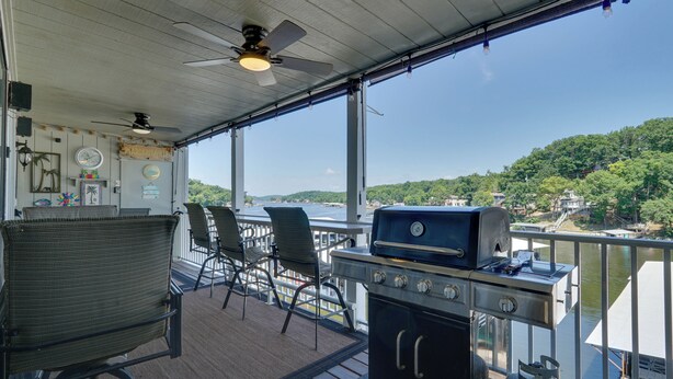 Une terrasse couverte avec un barbecue, des chaises et une vue sur une rivière.