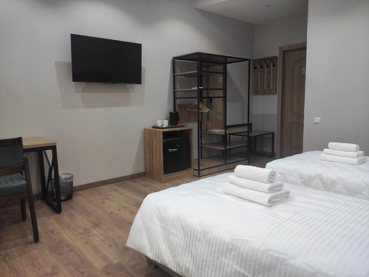 A hotel room with two beds, a TV, a wardrobe, and a desk.