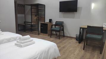 A hotel room with two beds, a desk, a chair, a TV, and a wardrobe.