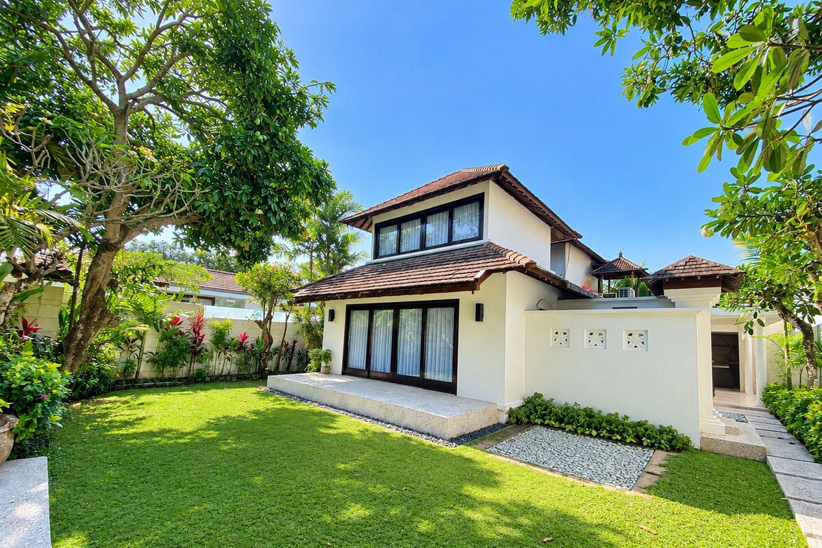 A modern two-story house with a well-maintained lawn and a variety of plants.