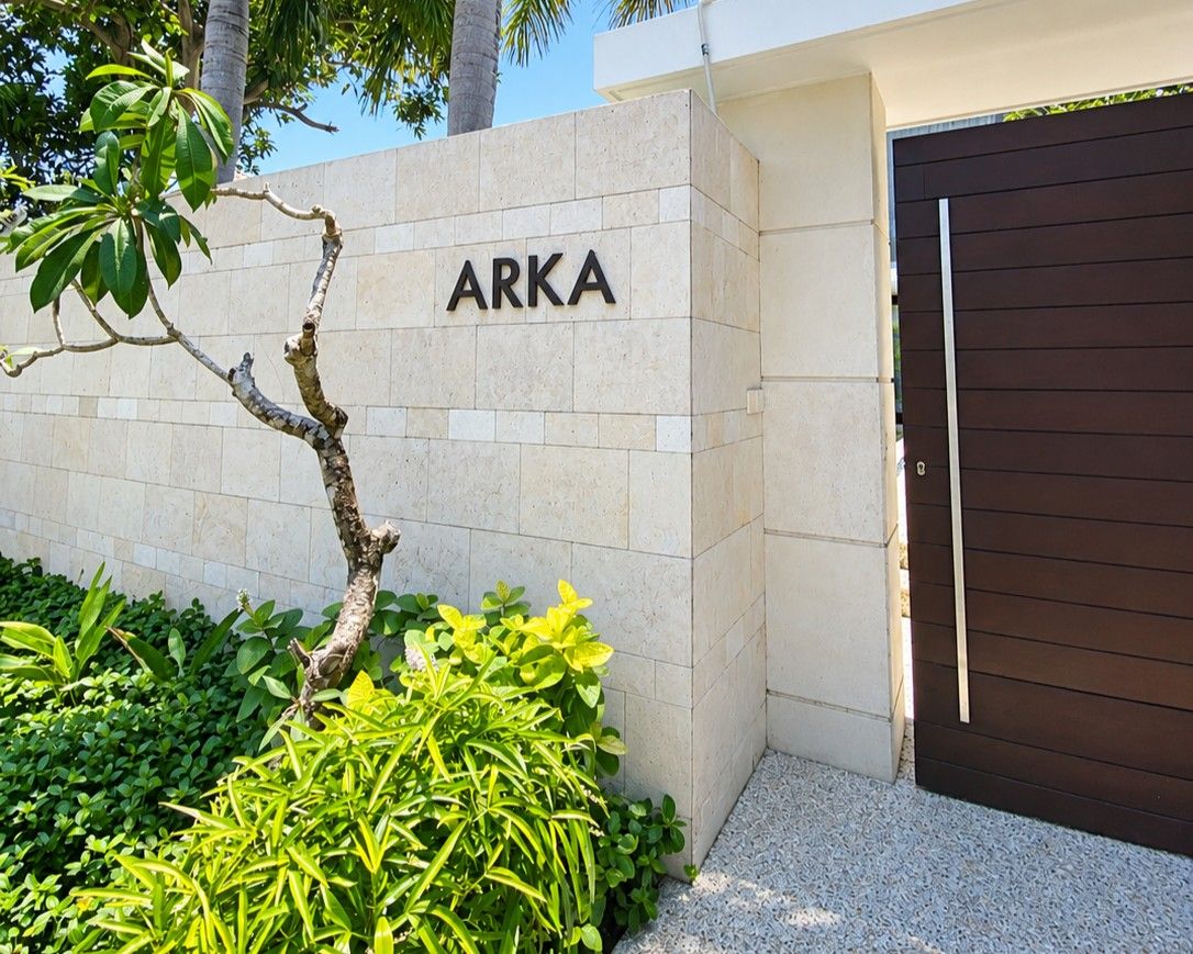 Una entrada de edificio con un letrero que dice 'ARKA' y una puerta de madera oscura.
