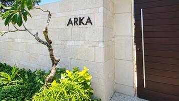 Una entrada de edificio con un letrero que dice 'ARKA' y una puerta de madera oscura.