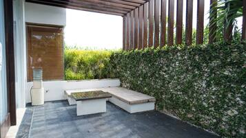 Een terras met een bank en tafel, omringd door een muur met klimplanten.