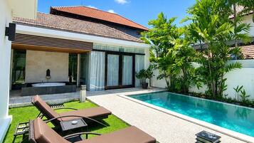 Una casa moderna con piscina, mobiliario exterior y jardín.